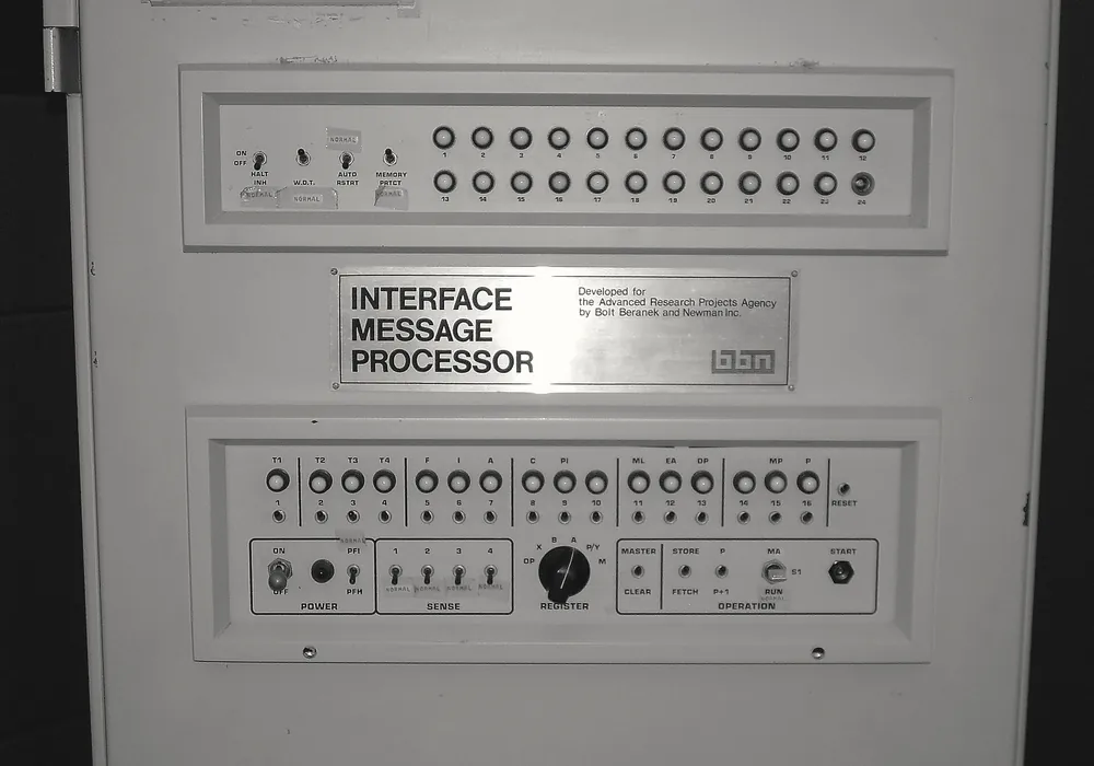 Mặt trước một tủ máy màu xám với hai hàng công tắc và đèn, tấm biển ghi Interface Message Processor.