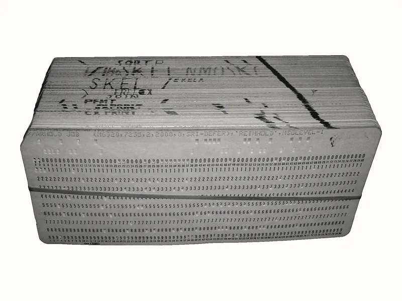Một chồng thẻ đục lỗ dày được buộc bằng dây chun, mặt trên có chữ viết tay.
