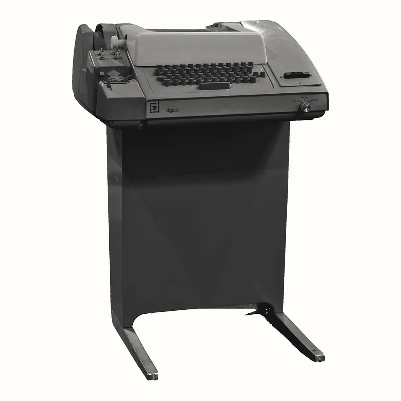 Máy Teletype Model 33 ASR đặt trên chân đế kim loại, gồm bàn phím và bộ phận in giấy.